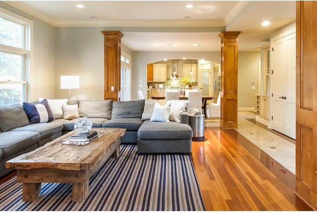 living room with light hardwood / wood-style flooring, ornamental molding, and ornate columns