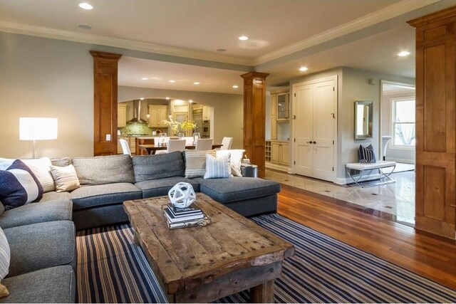 living room featuring light hardwood / wood-style flooring, ornamental molding, and ornate columns