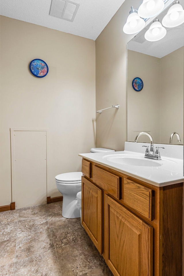 bathroom featuring vanity, a textured ceiling, and toilet