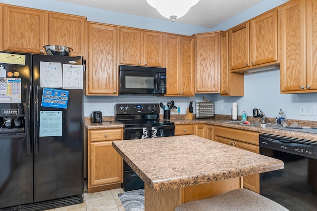 kitchen featuring sink, light tile patterned floors, a kitchen bar, and black appliances