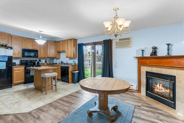 kitchen with decorative light fixtures, a wall mounted AC, a kitchen breakfast bar, a center island, and black appliances