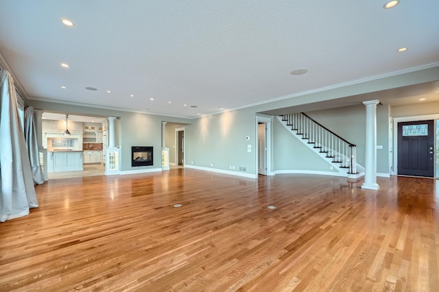 unfurnished living room with crown molding, a multi sided fireplace, light hardwood / wood-style floors, and ornate columns