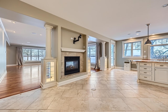 interior space featuring ornate columns, ornamental molding, tile patterned flooring, and a fireplace