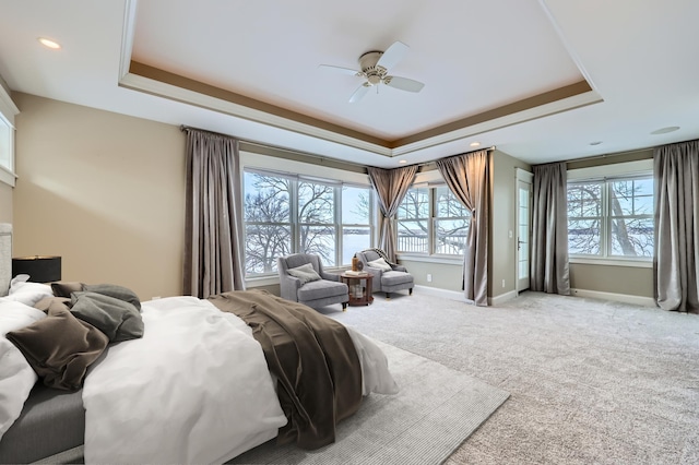 carpeted bedroom featuring ceiling fan and a tray ceiling