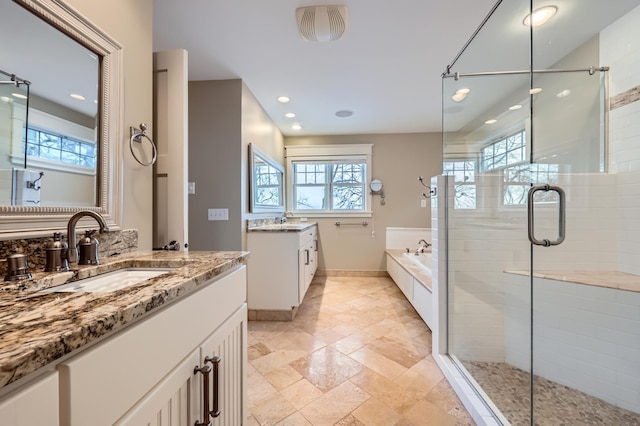 bathroom featuring independent shower and bath, vanity, and a wealth of natural light