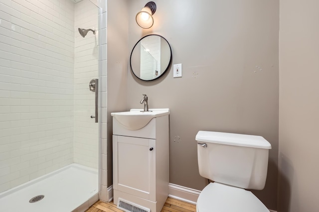 bathroom with tiled shower, vanity, toilet, and hardwood / wood-style floors