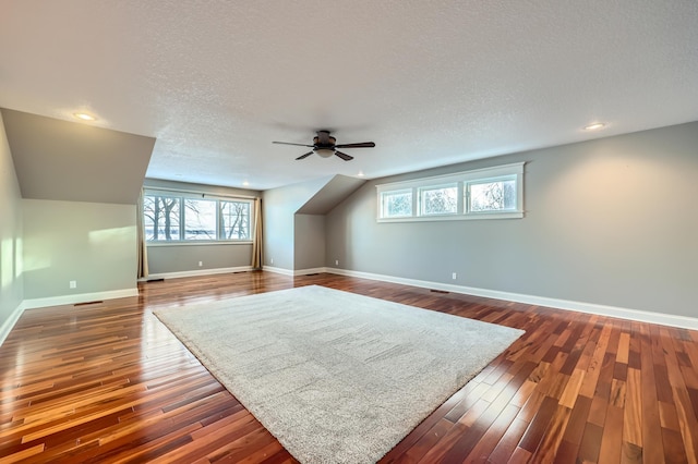 additional living space featuring a healthy amount of sunlight, dark hardwood / wood-style floors, and a textured ceiling