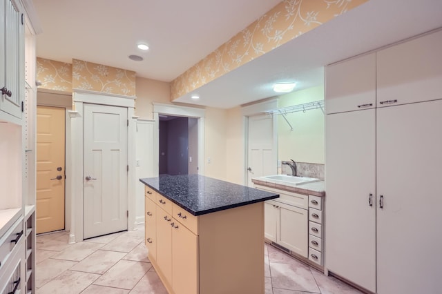 kitchen with white cabinetry, sink, dark stone counters, and a kitchen island