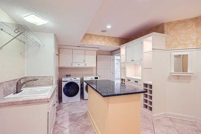 laundry area featuring cabinets, sink, washing machine and clothes dryer, and a textured ceiling