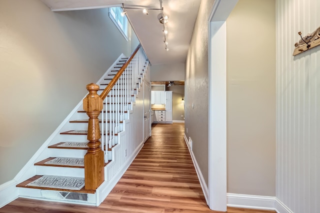 staircase featuring hardwood / wood-style flooring and track lighting