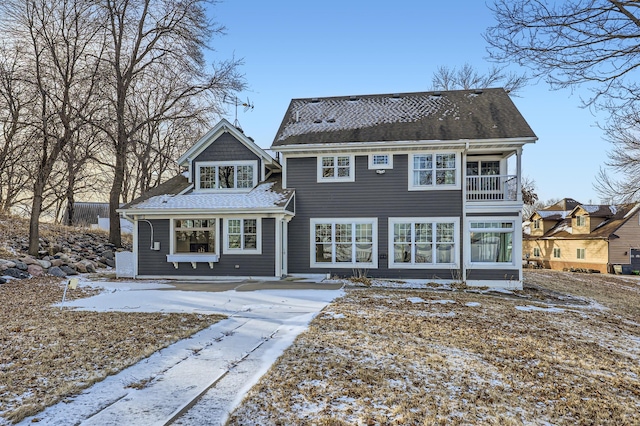 snow covered rear of property with a balcony