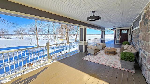 snow covered deck with an outdoor living space with a fire pit