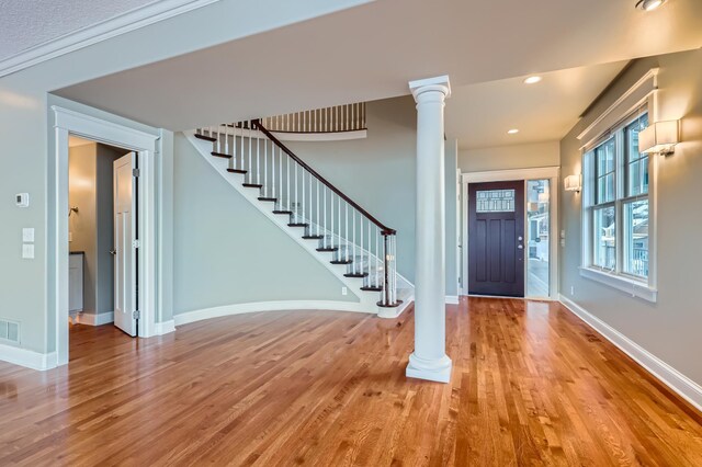 foyer entrance featuring baseboards, decorative columns, stairway, and wood finished floors