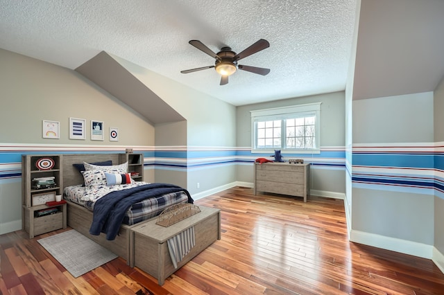 bedroom with a textured ceiling, hardwood / wood-style flooring, and baseboards