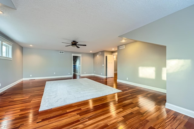 empty room with visible vents, ceiling fan, a textured ceiling, baseboards, and hardwood / wood-style flooring