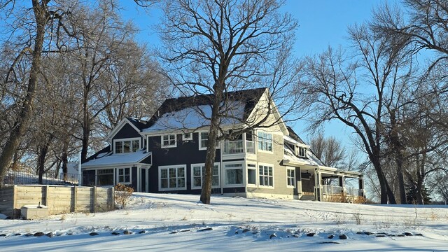 view of front of house featuring a balcony, a sunroom, and fence