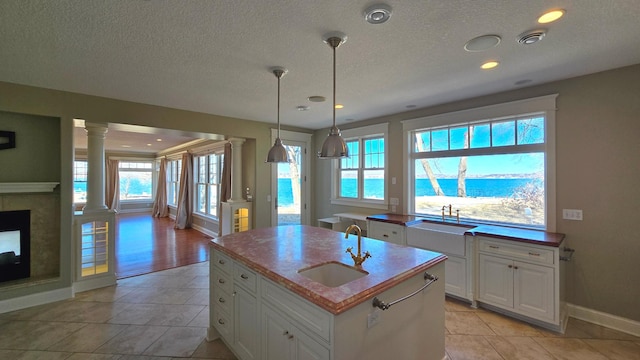 7 County Road 12 S, Buffalo, MN 55313 - kitchen with ornate columns, a sink, baseboards, a textured ceiling, and white cabinets