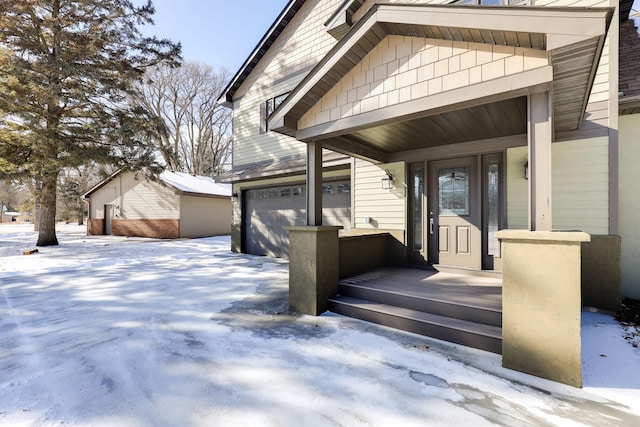 snow covered property entrance with a garage and covered porch