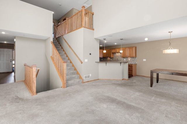 unfurnished living room featuring a towering ceiling and light colored carpet