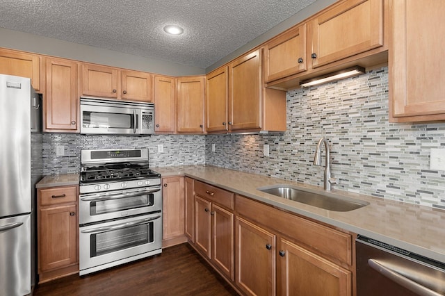 kitchen with appliances with stainless steel finishes, sink, dark hardwood / wood-style flooring, and decorative backsplash