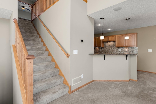 staircase featuring ceiling fan, carpet, and a textured ceiling