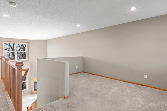 empty room with light colored carpet, a tile fireplace, and a textured ceiling