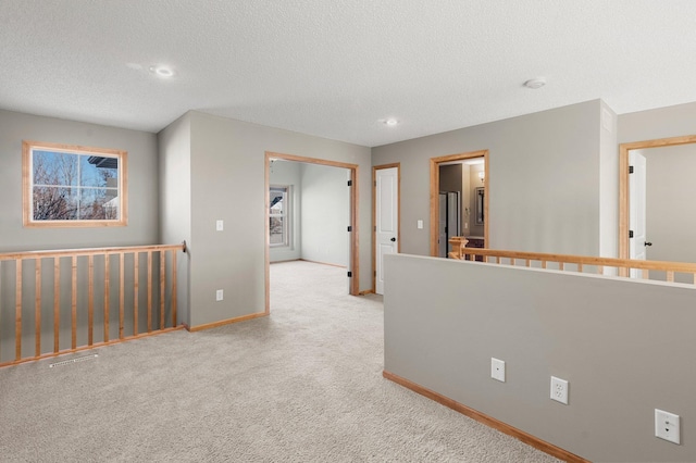 hall with light colored carpet and a textured ceiling