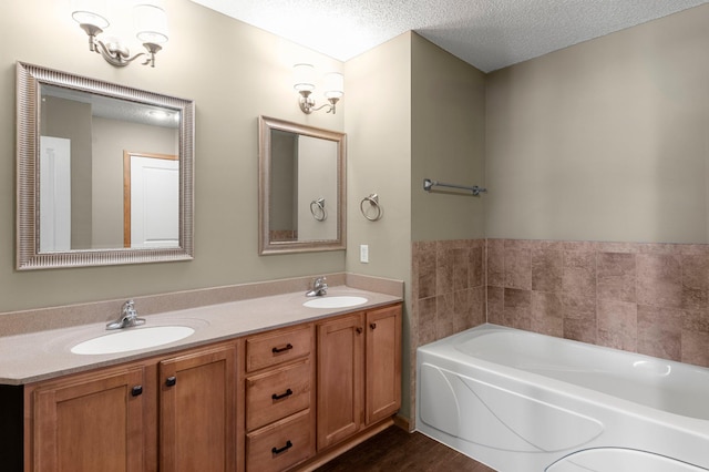 bathroom featuring vanity, a washtub, and a textured ceiling