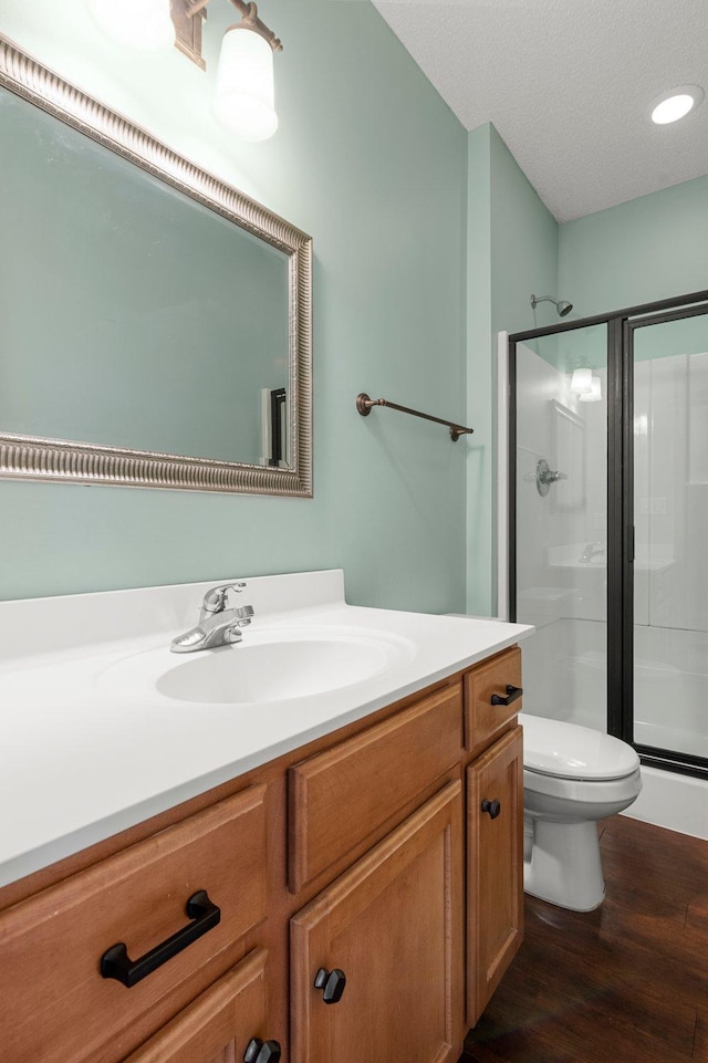 bathroom featuring hardwood / wood-style floors, vanity, a textured ceiling, toilet, and walk in shower