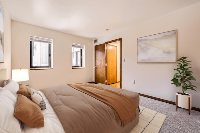 bedroom featuring baseboards, visible vents, and light colored carpet