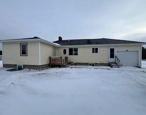 snow covered house featuring a garage