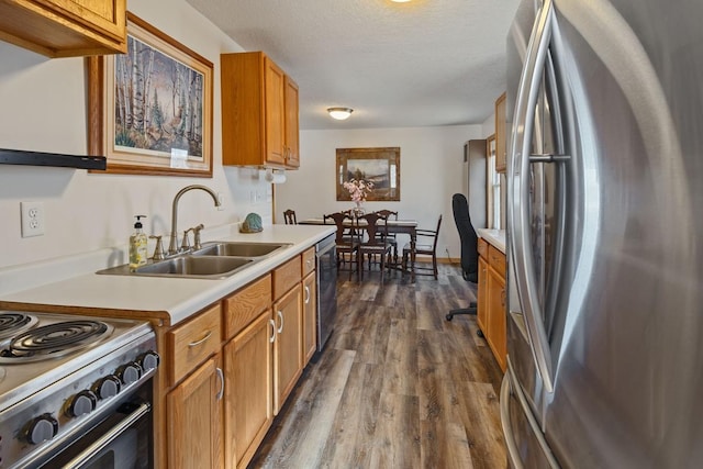 kitchen with dark wood finished floors, light countertops, appliances with stainless steel finishes, a textured ceiling, and a sink