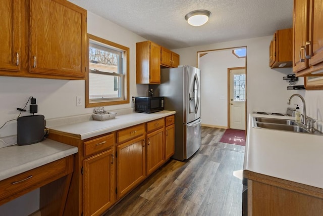 kitchen with brown cabinets, stainless steel refrigerator with ice dispenser, black microwave, and a sink