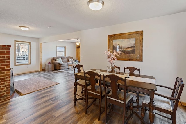 dining space with baseboards, a textured ceiling, and wood finished floors