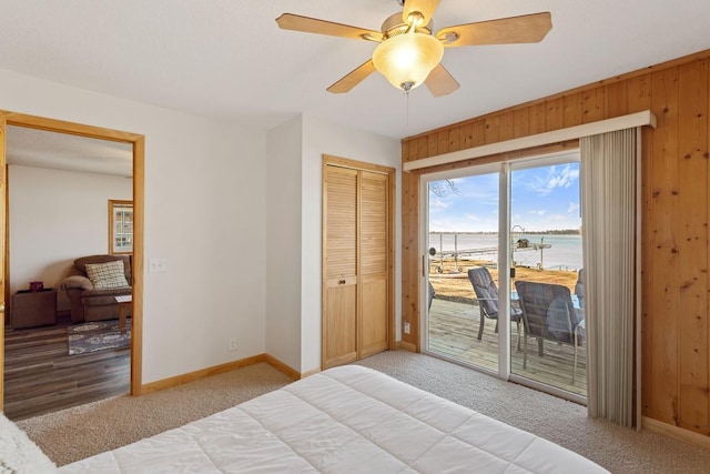 bedroom with access to outside, light colored carpet, and wood walls