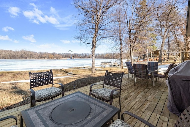 wooden terrace with a water view and outdoor dining space