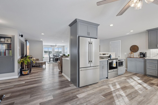 kitchen with stainless steel appliances, light hardwood / wood-style floors, decorative backsplash, and gray cabinetry