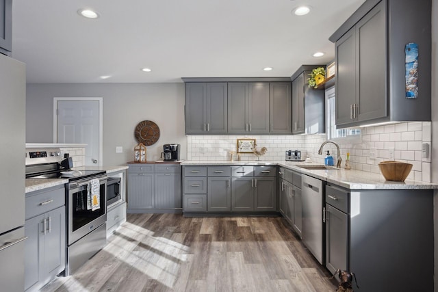 kitchen featuring light stone counters, sink, gray cabinets, and stainless steel appliances