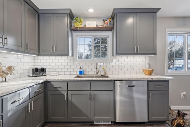 kitchen with gray cabinetry, sink, light stone counters, and stainless steel dishwasher