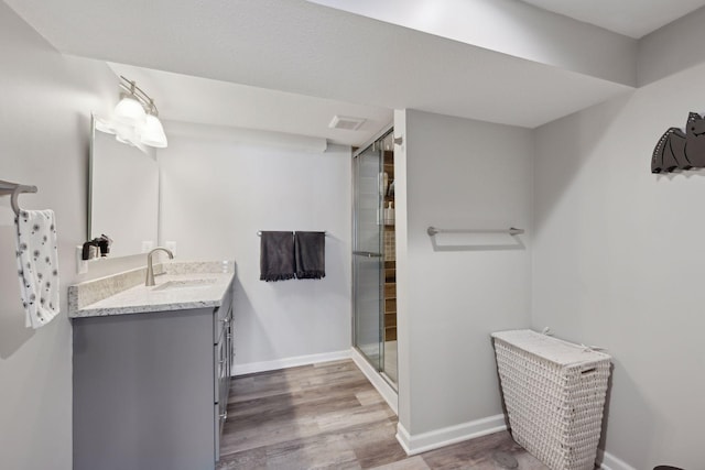 bathroom featuring vanity, wood-type flooring, and a shower with shower door