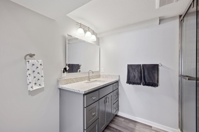 bathroom featuring vanity, hardwood / wood-style floors, a textured ceiling, and an enclosed shower