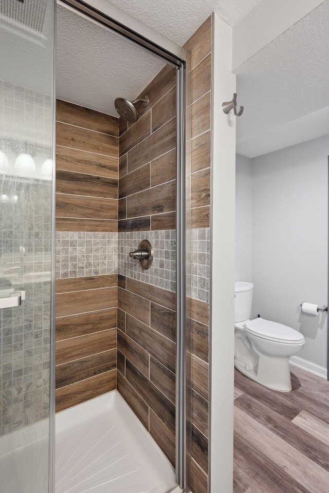 bathroom featuring wood-type flooring, an enclosed shower, a textured ceiling, and toilet