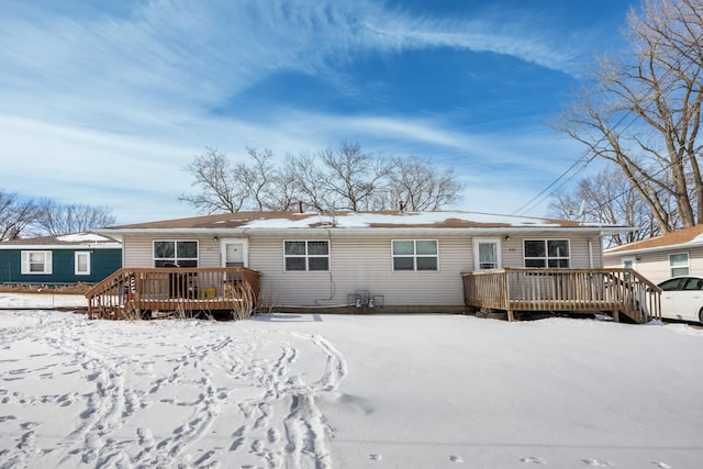 snow covered back of property featuring a wooden deck