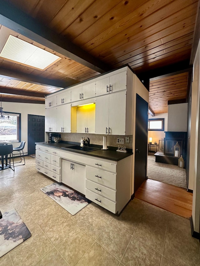 kitchen featuring sink, white cabinetry, beam ceiling, tasteful backsplash, and a healthy amount of sunlight