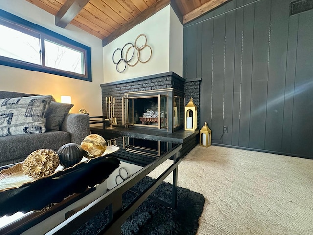 living room with vaulted ceiling with beams, wooden walls, carpet, a fireplace, and wooden ceiling