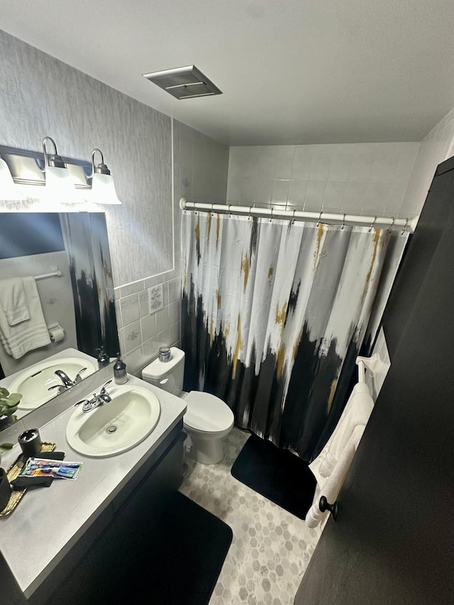 bathroom featuring vanity, toilet, and tile walls