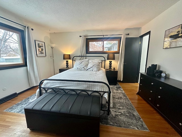 bedroom featuring a textured ceiling, multiple windows, and light wood-type flooring