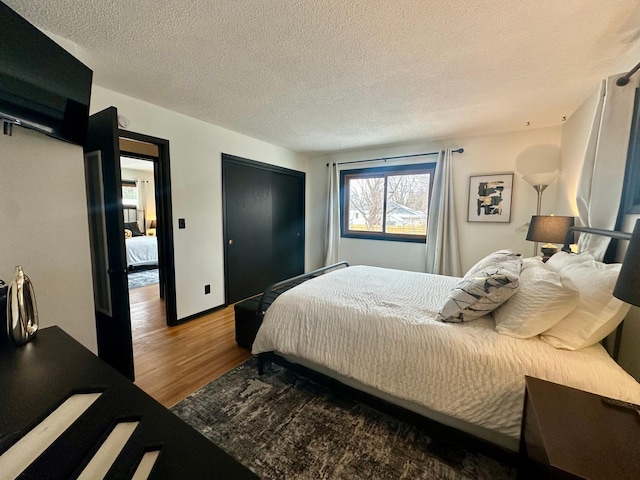 bedroom with hardwood / wood-style flooring, a textured ceiling, and a closet