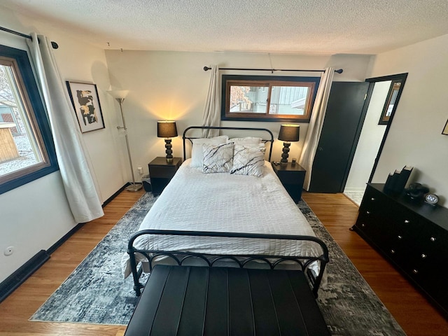 bedroom featuring hardwood / wood-style floors, multiple windows, and a textured ceiling