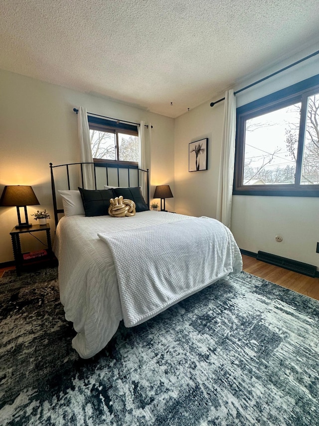 bedroom with dark hardwood / wood-style floors and a textured ceiling